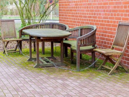 groene aanslag onder op de tegels onder een houten tuinstel