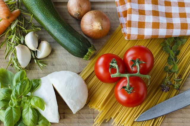 Verse basilicum en andere kruiden in keuken, daarnaast mozzarella en tomaat