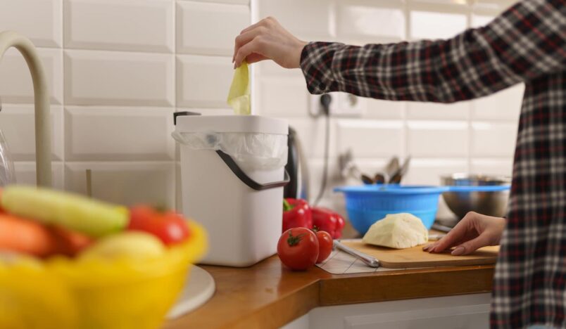 vrouw die bokashi compost maakt in de keuken