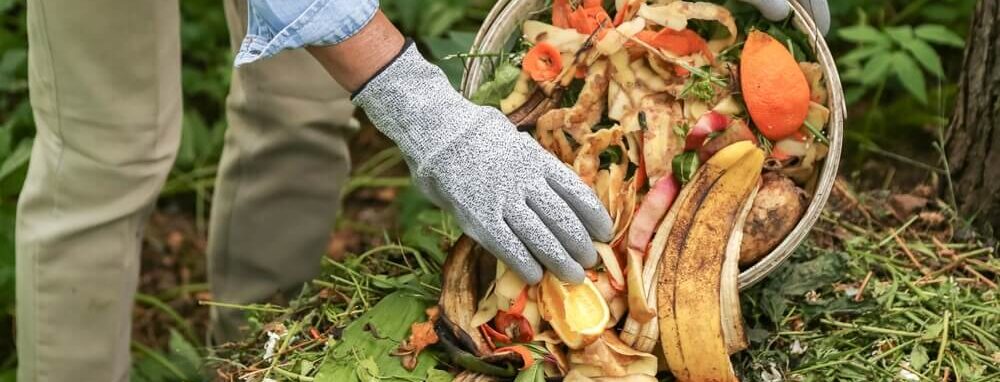 Iemand gooit fruit- en groenteschillen in de tuin