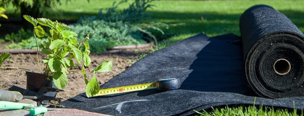 Worteldoek en meetlint op tuinbodem
